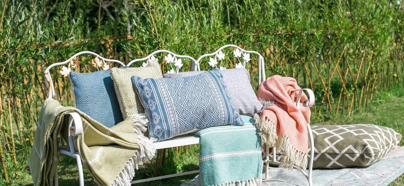 Throws and cushions by Weaver Green on a cream bench.