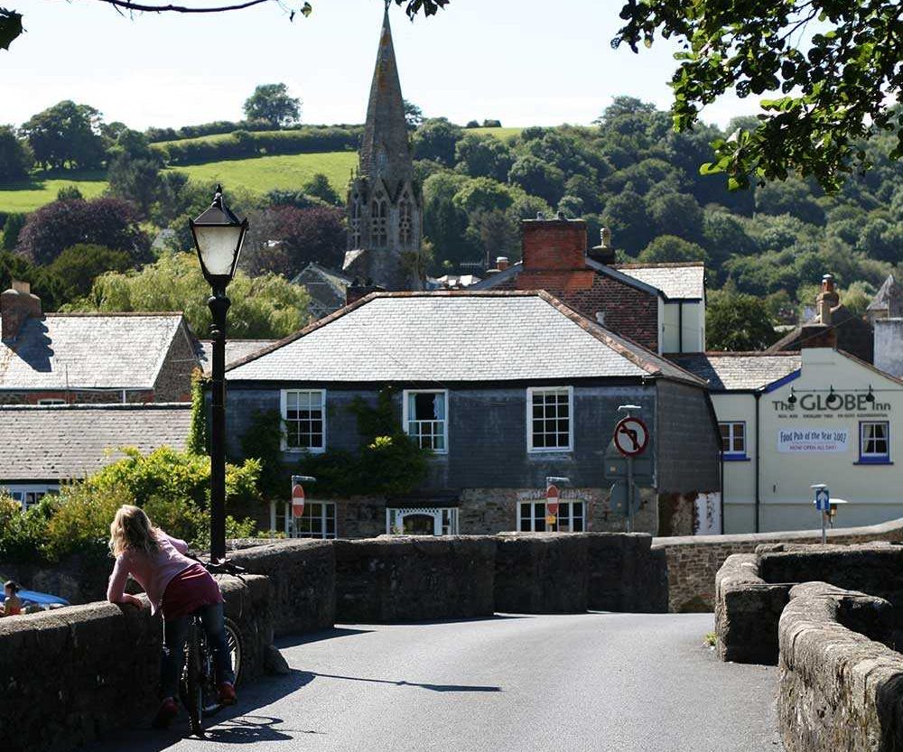 Bridge leading towards Lostwithiel, Cornwall with houses and a church behind.