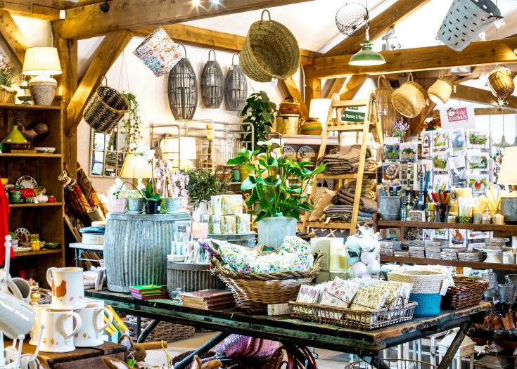 A shop area filled with gifts and homeware both on tables and hanging from the ceiling.